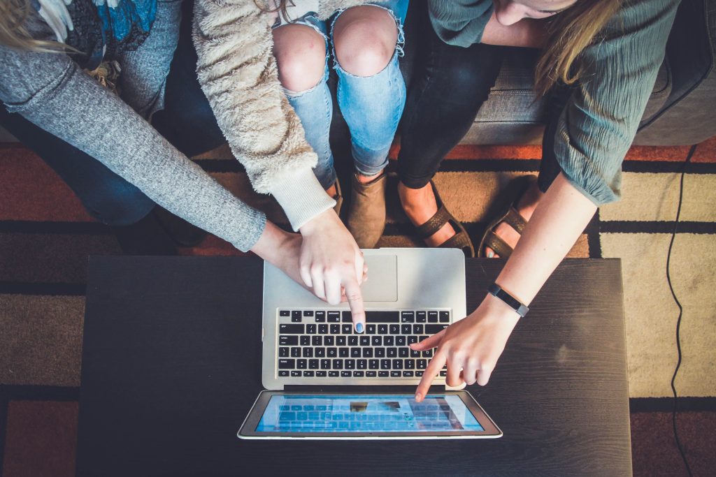 Three people pointing to an open laptop screen