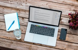 Laptop, notebook, phone, and water glass on a table