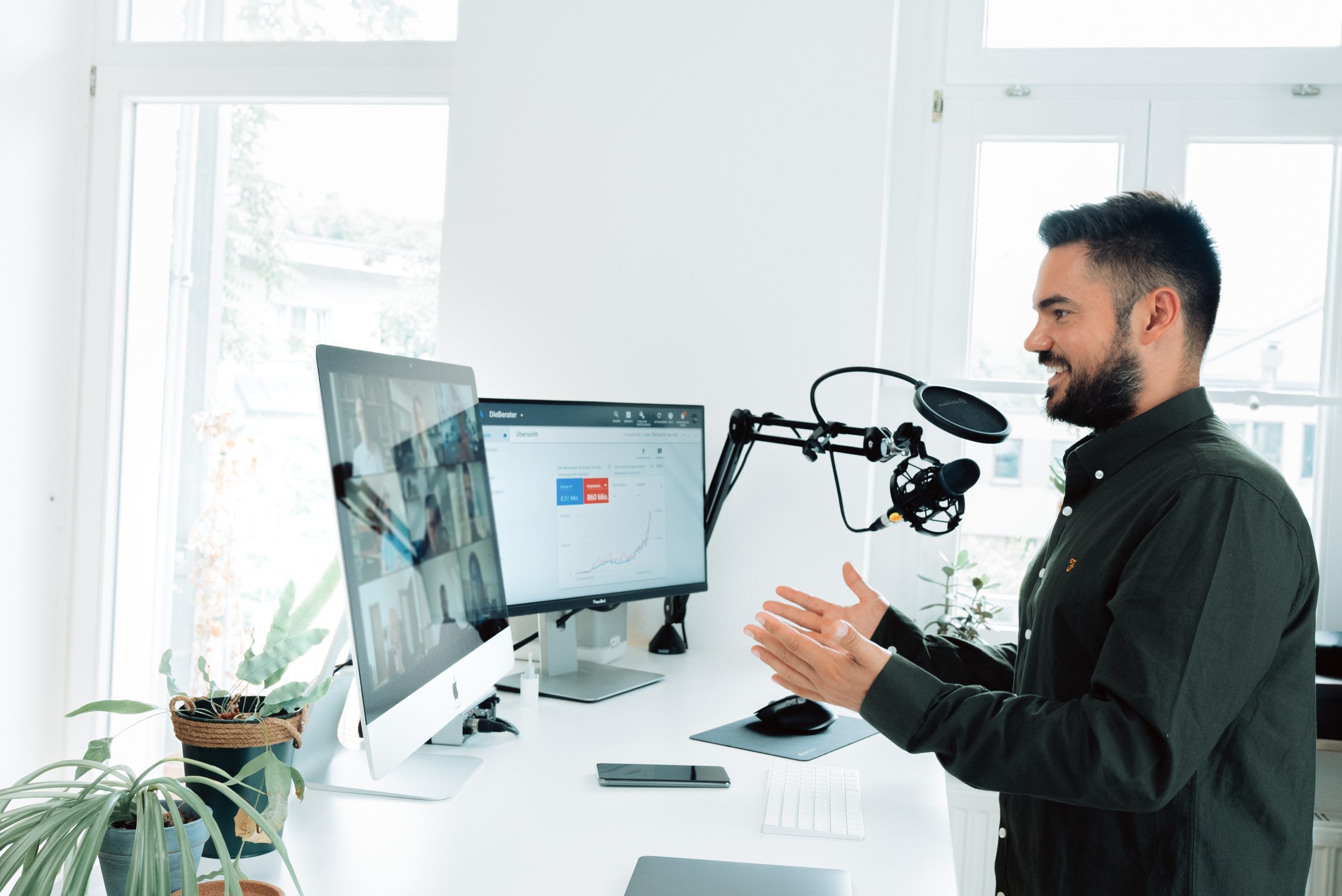 Man conducting a webinar in front of two computer screens and a microphone
